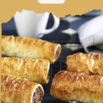 Golden homemade sausage rolls with beef and sausage mince, displayed on a rustic wooden board, ready to serve.